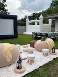 Cozy outdoor lounge with two cream bean bags, yellow blankets, ottomans and lanterns on a patterned rug