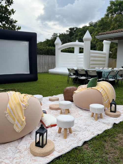 Cozy outdoor lounge with two cream bean bags, yellow blankets, ottomans and lanterns on a patterned rug