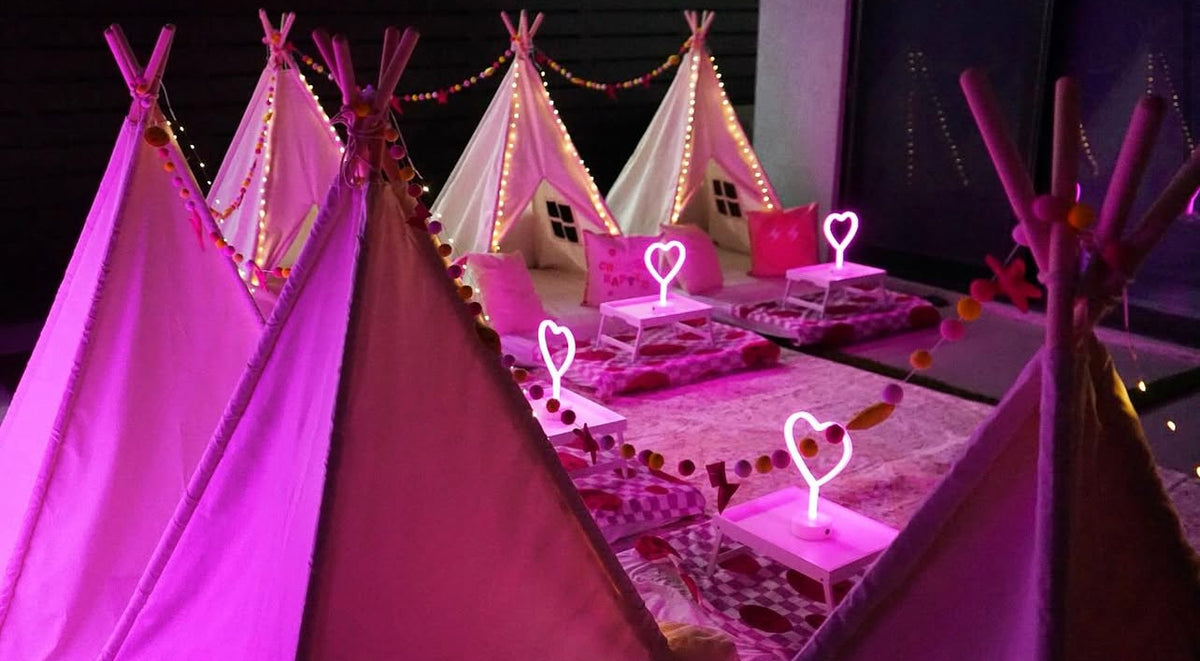 Teepees glowing with pink heart lamps and twinkle lights