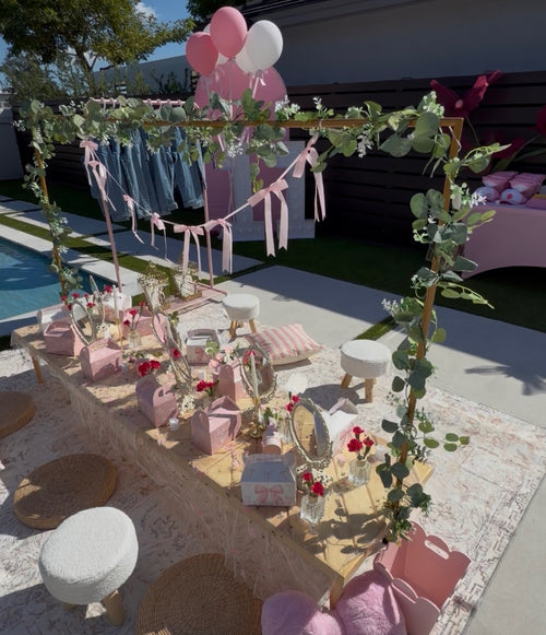 Spa party table with individual mirrors, pink gift boxes, flowers and ribbon garland